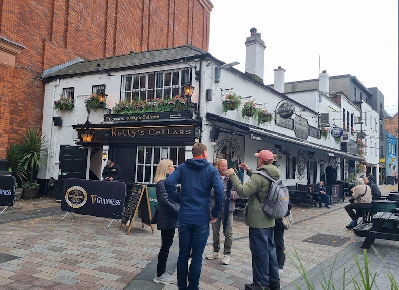A pub named 'Kelly's Cellars' with Guinness branding, a brick building, and a paved street. 1