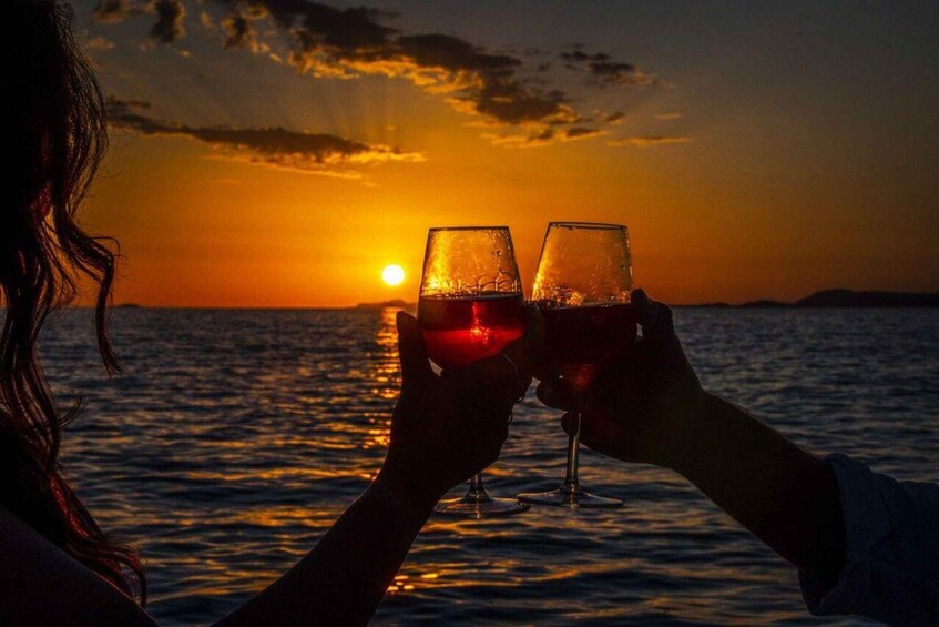 Two people toasting with wine glasses against a sunset over the ocean. 2