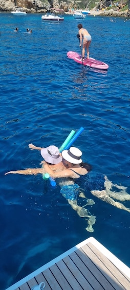 A person swimming in a body of water with a paddleboard in the background. 5