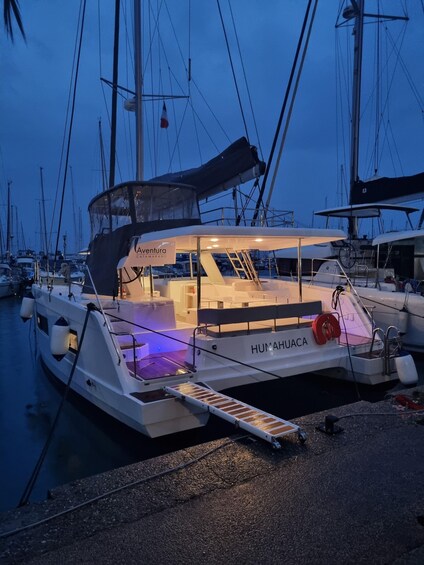 A white boat named 'HUMAHUACA' docked at a marina with other boats, under a twilight sky. 5