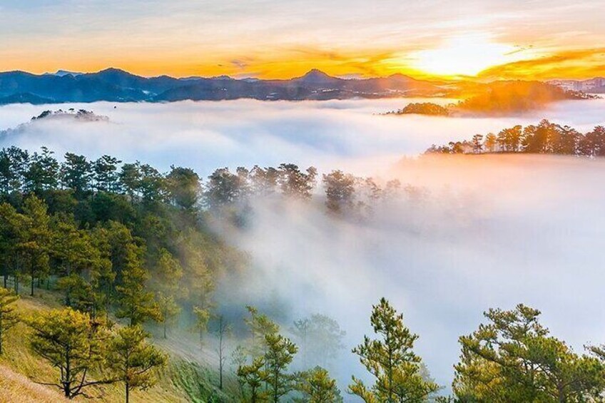 A sunrise over a forested mountain range with mist. 4