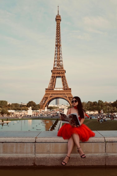 A person in a red dress sitting on a ledge with the Eiffel Tower in the background. 1