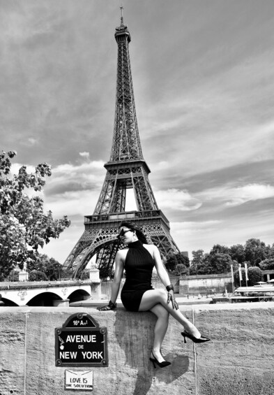 A person sitting on a concrete structure with the Eiffel Tower in the background. 5