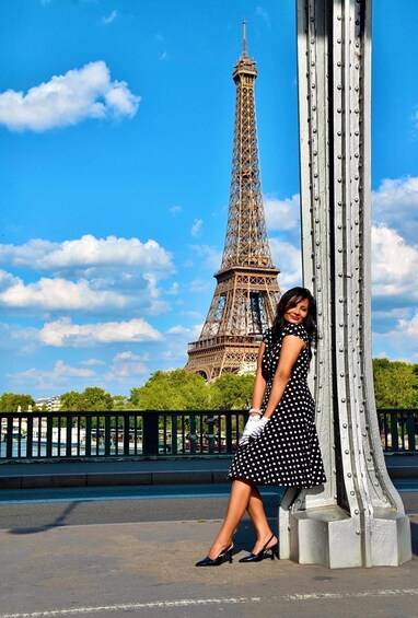 A person in a polka dot dress standing next to a metal structure with the Eiffel Tower in the background. 2
