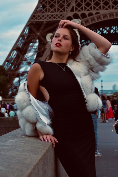 A person leaning against the Eiffel Tower with a fur coat. 1