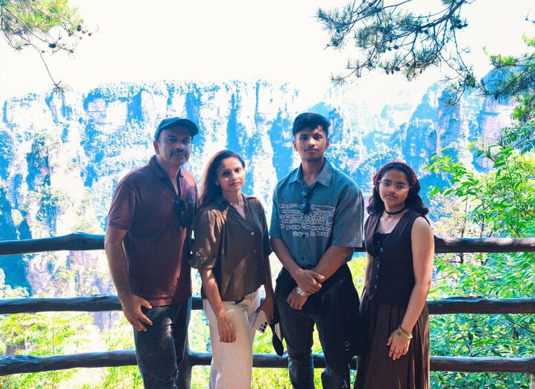 A group of people standing in front of a scenic cliff with greenery. 3