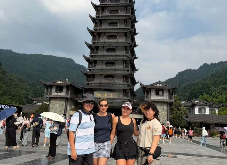A group of people posing in front of a traditional multi-tiered pagoda with a mountainous backdrop. 5