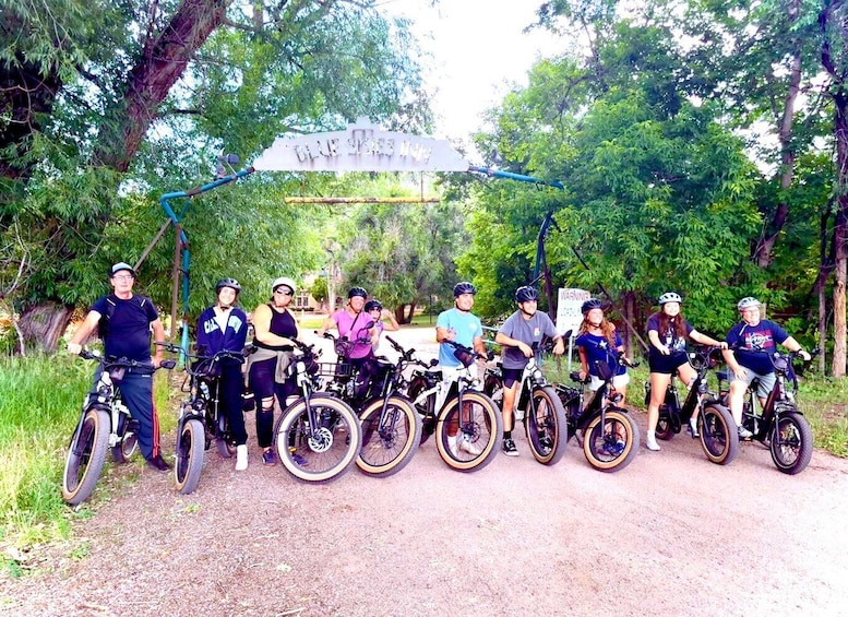A group of cyclists at a trail entrance with a sign reading 'BLUE SKY HILL'. 2