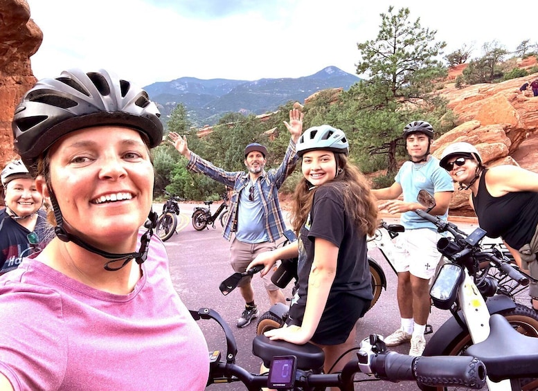 A group of people on electric bikes in a rocky outdoor setting with mountains in the background. 5
