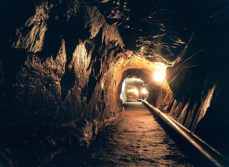 A tunnel with rough rock walls and a single light source at the end. 2