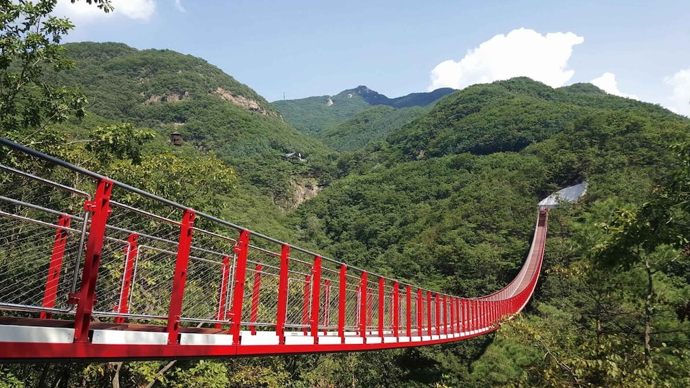 A red suspension bridge in a mountainous area. 5