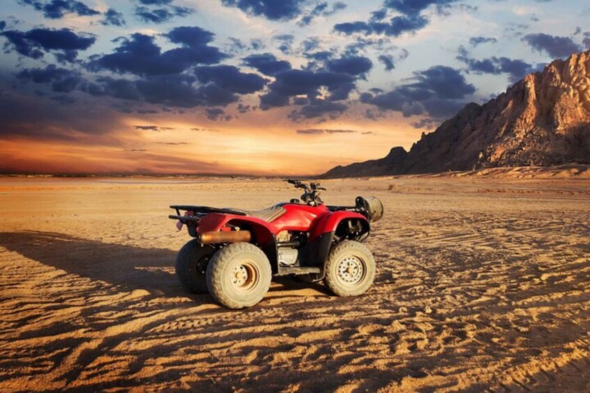 A red quad bike on a sandy desert landscape with a mountain in the background. 5