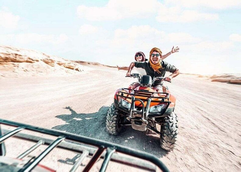 Two people on an ATV in a desert. 1
