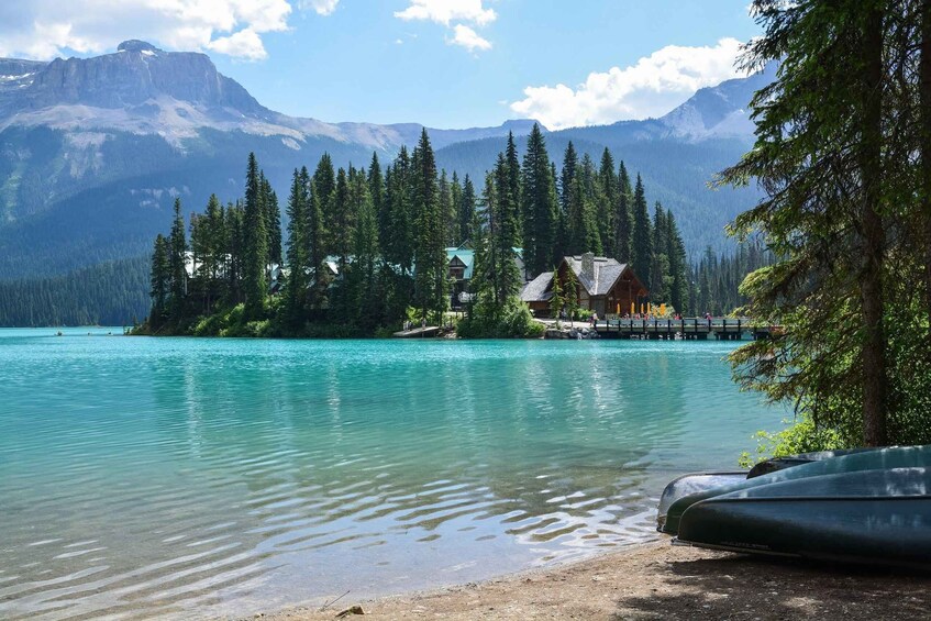 A lake with clear turquoise water, surrounded by dense green forest and mountains in the background. 1