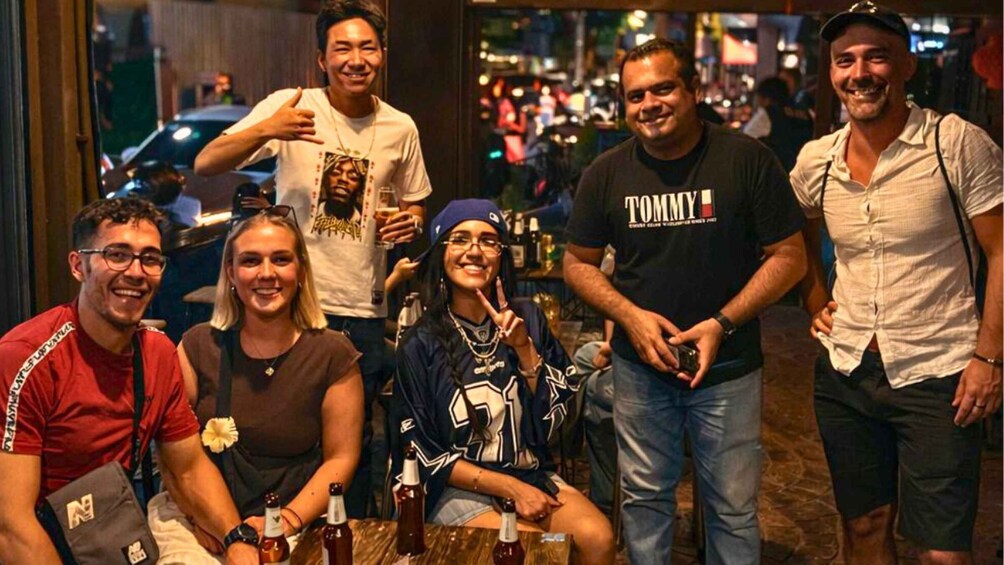A group of people at a bar with bottles and glasses on the table. 4