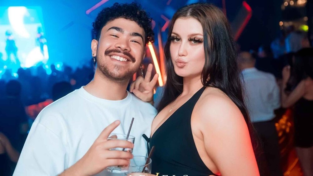 Two people at a social event with a neon-lit background. 1