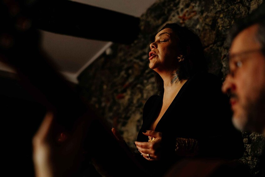 A person in a dark setting with a stone wall in the background. 2