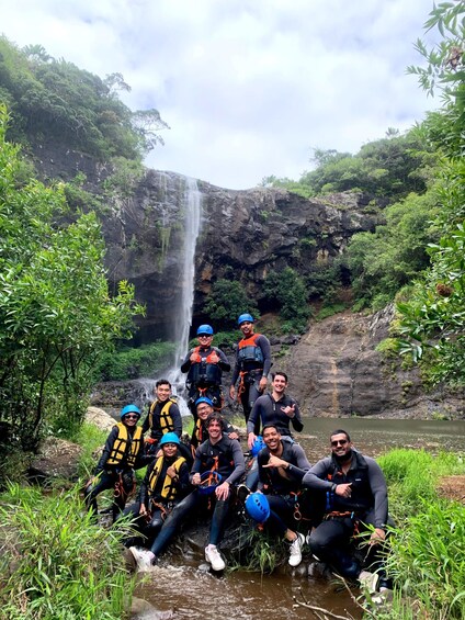 A group of people in a forested area with a waterfall. 5