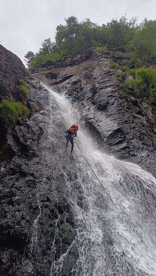 A person rappelling down a waterfall in a rocky terrain. 2