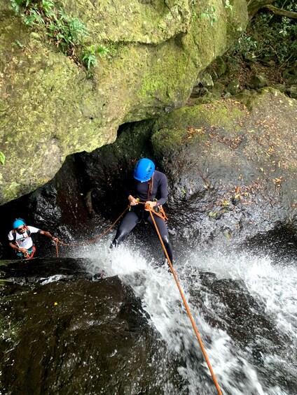 Two individuals rappelling down a rocky waterfall. 3