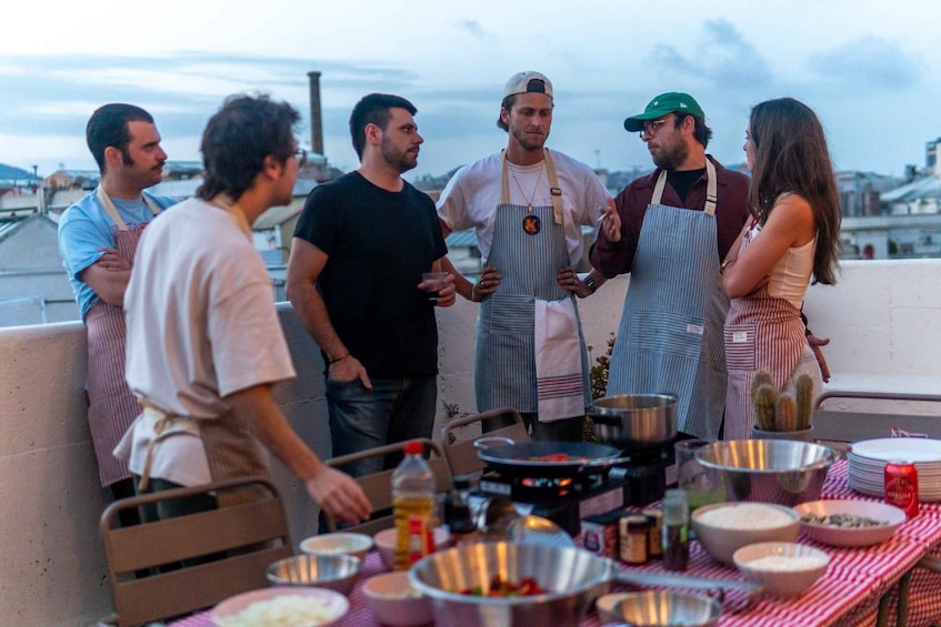 A group of people around a table with cooking equipment and ingredients, suggesting a cooking activity. 1
