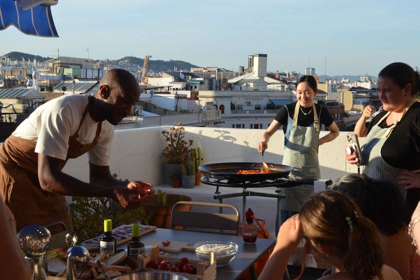 A group of people cooking outdoors on a rooftop with a cityscape in the background. 5