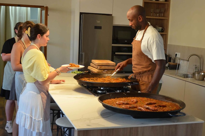 A person cooking in a kitchen with a large pan on the stove. 3