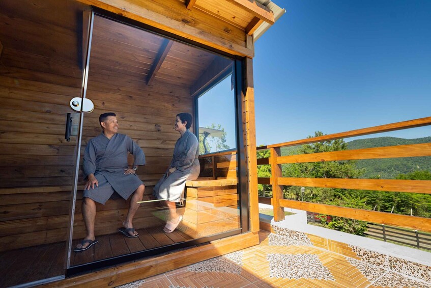 A wooden cabin with a sliding glass door, a wooden deck, and a view of a green landscape. 4