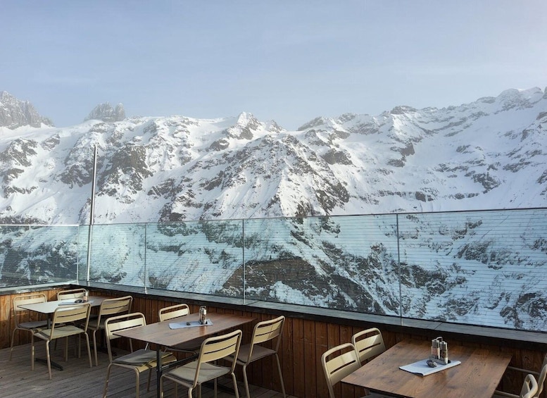 A restaurant with outdoor seating overlooking snow-capped mountains. 1