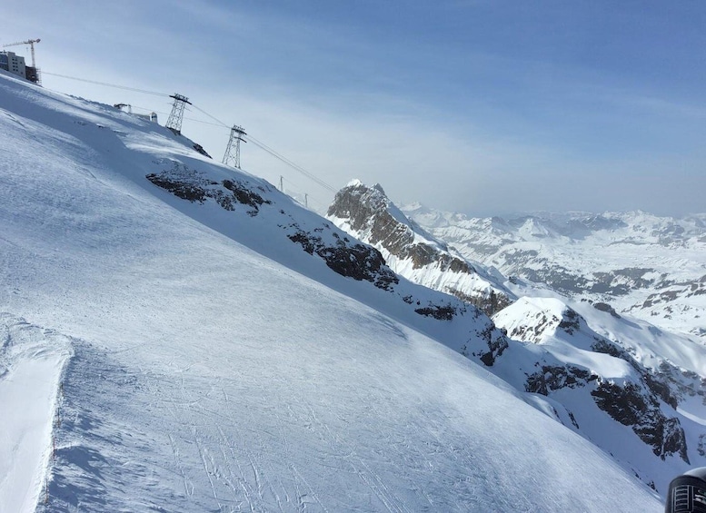 A snow-covered mountain slope with power lines and a construction crane in the background. 3