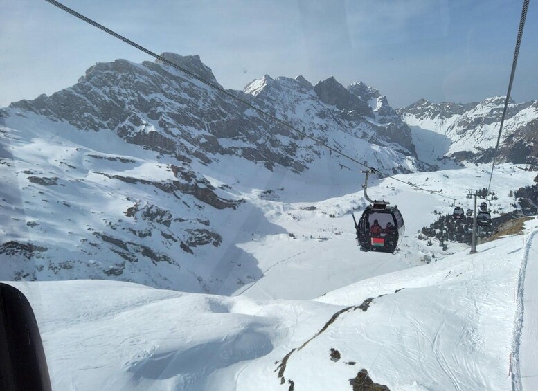 A cable car ascending a snowy mountain with rocky peaks in the background. 5
