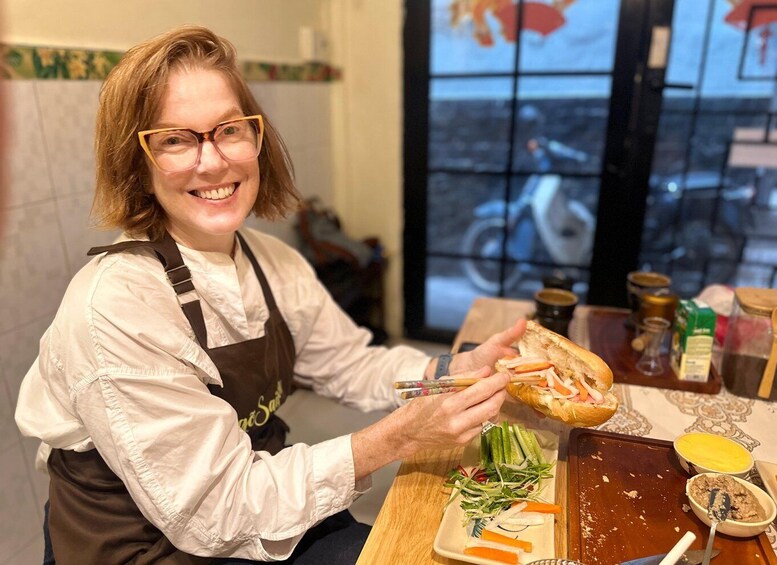 A person in a kitchen preparing food, with vegetables, condiments, and a bicycle visible in the background. 1