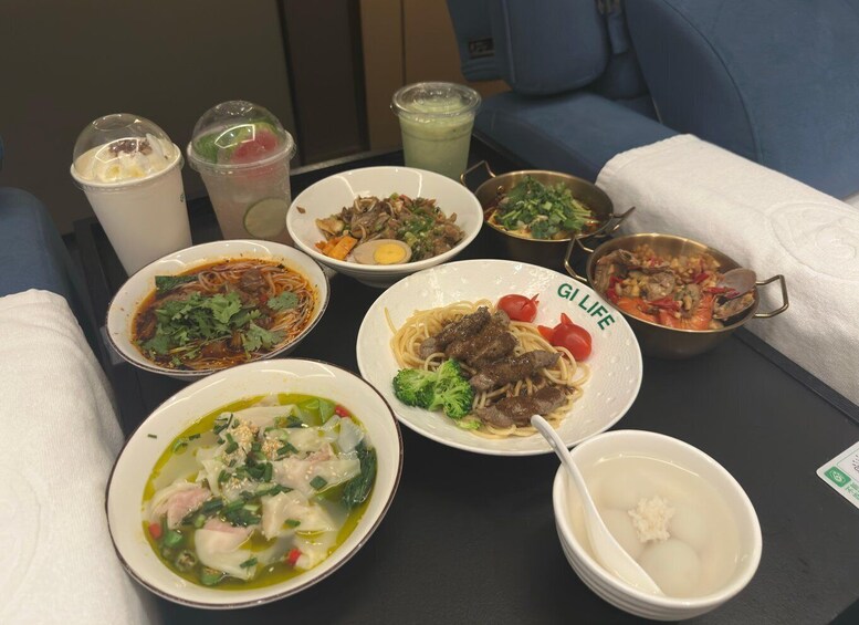 A variety of Asian dishes including noodles, soup, and seafood, served on a table in a dining setting. 1