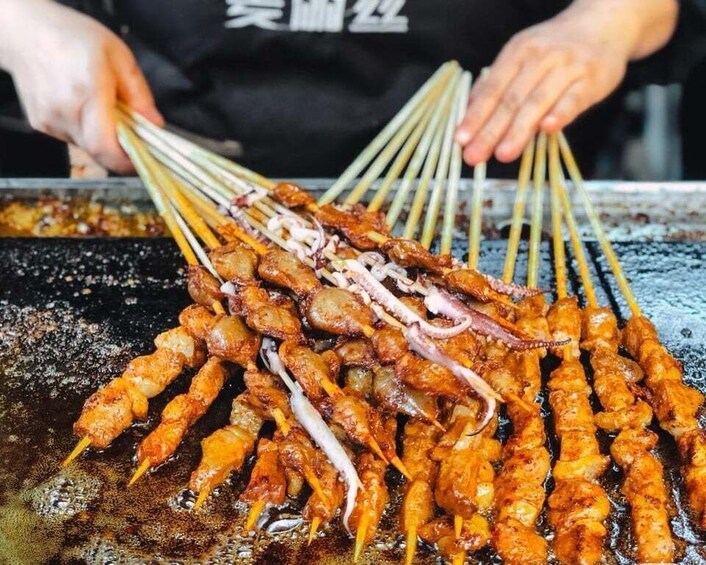 Skewers of grilled meat and squid being prepared on a grill. 5