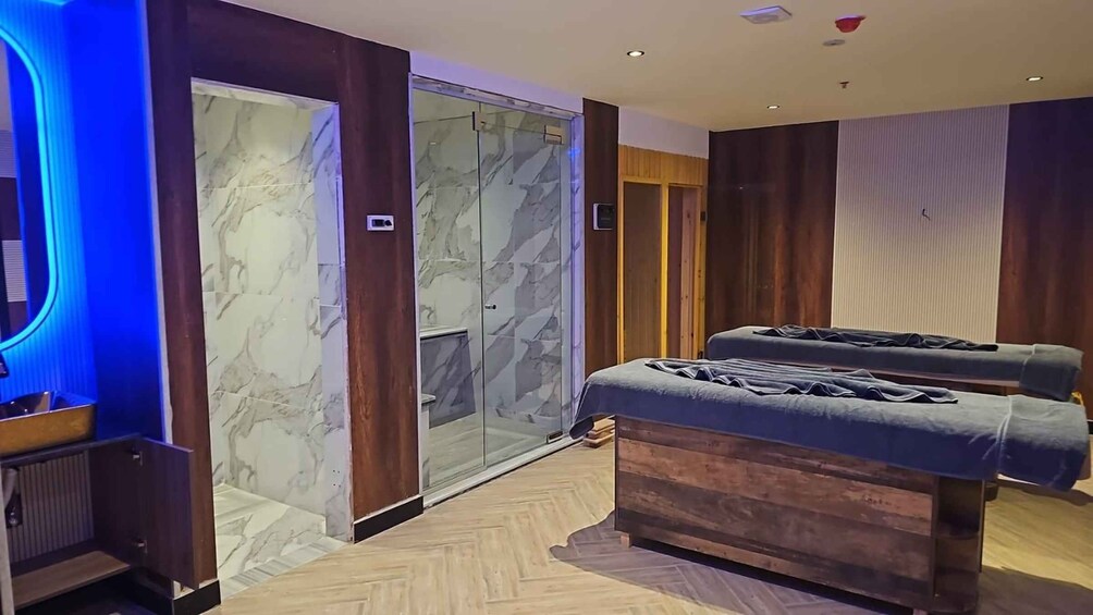 A modern spa room with marble walls, wooden paneling, and a massage table. 2