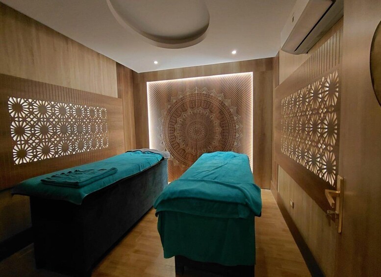 A spa room with two massage tables, wooden paneling, and intricate wall designs. 4