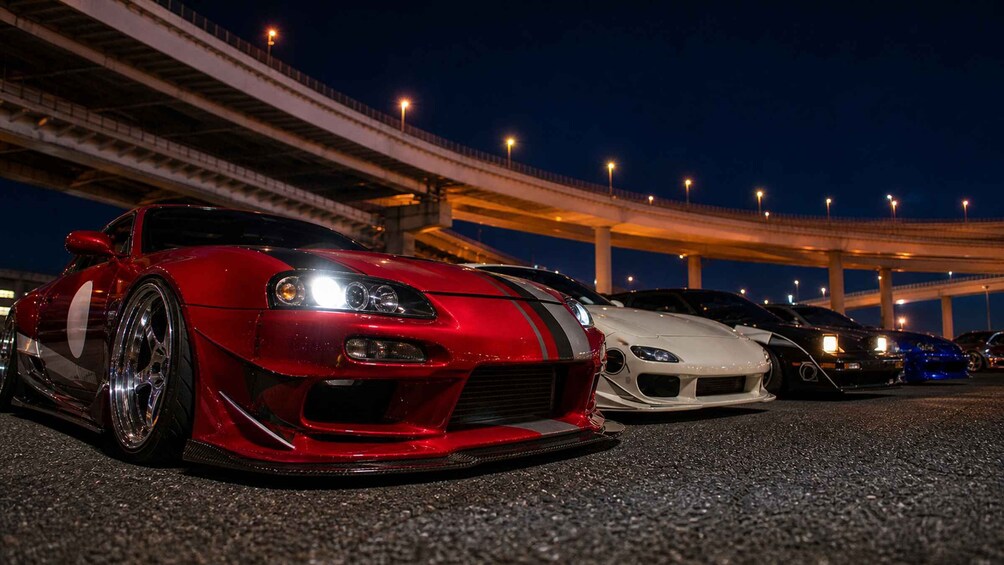 A red sports car parked under an overpass at night. 4