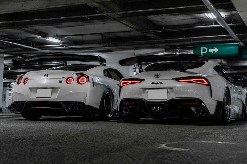 Two white sports cars parked in a dimly lit underground parking garage. 5