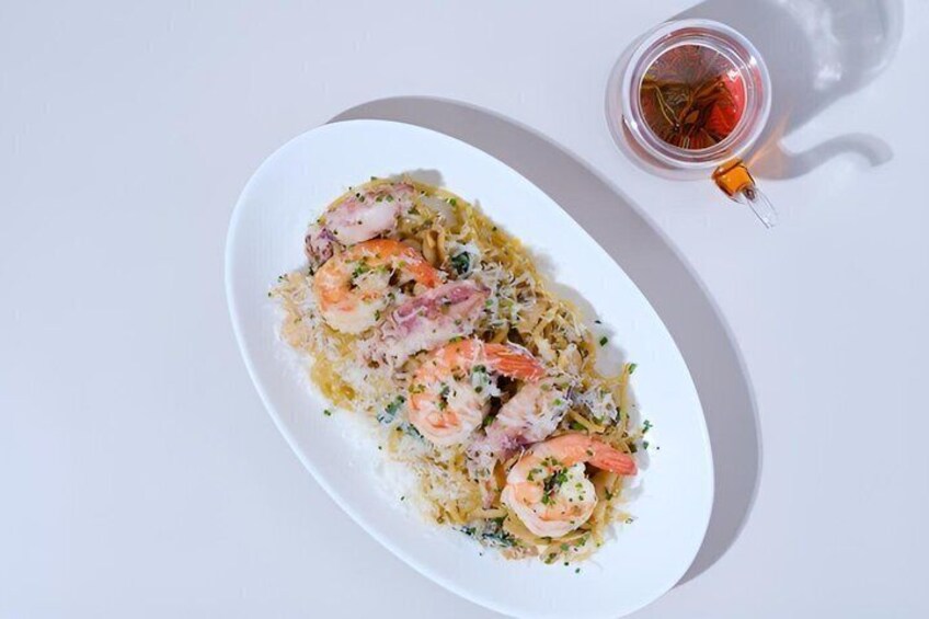 A plate of shrimp and rice with a glass of red drink beside it. 5