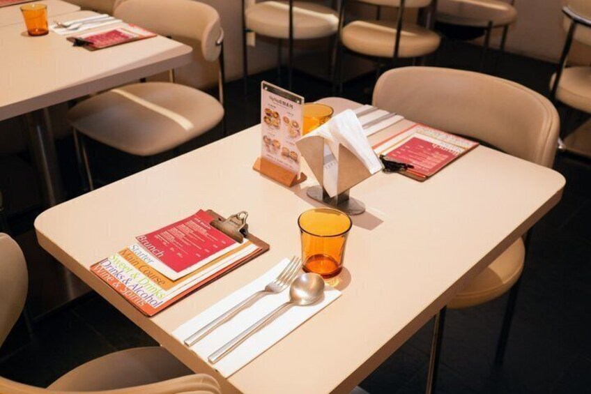 A restaurant table set with menus, cutlery, and a glass. 3