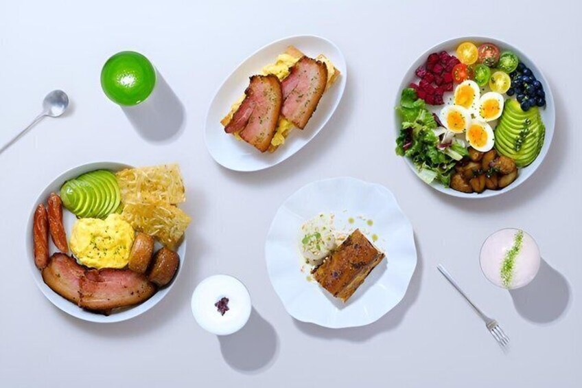 A variety of breakfast dishes including eggs, bacon, and avocado on a white table. 1