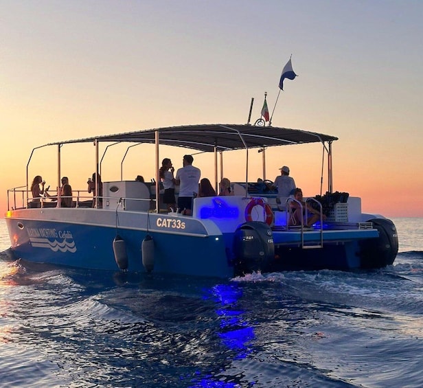 A boat named CAT33S with people on board, moving through the water during sunset. 1