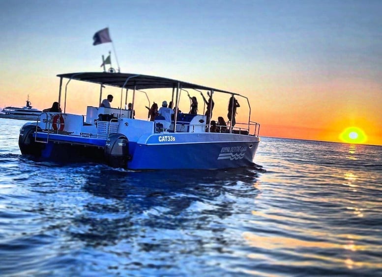 A blue boat named CAT33s on calm waters with a sunset in the background. 4