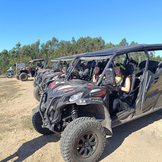 A group of off-road vehicles parked on a dirt ground with trees in the background. 5