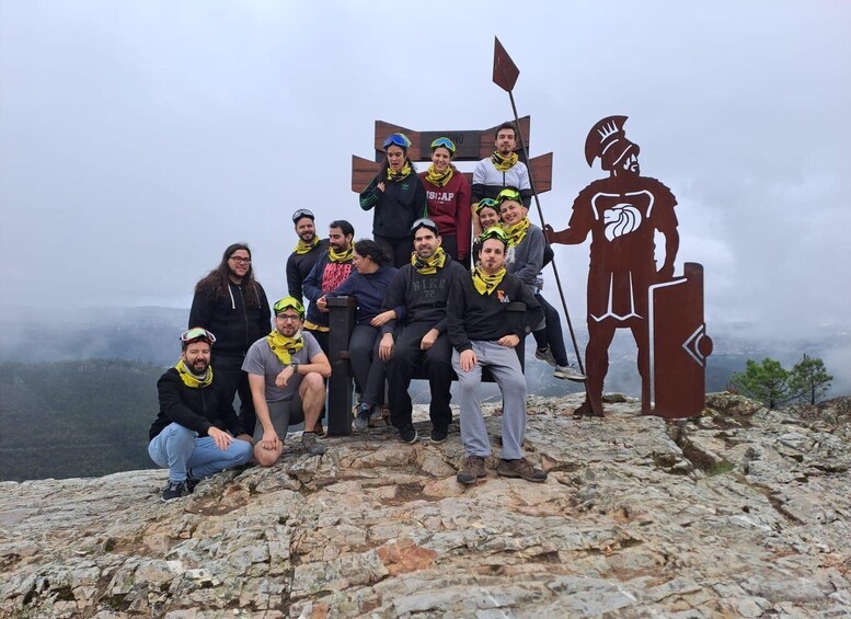 A group of people on a rocky mountain peak with a large bronze statue of a warrior. 4