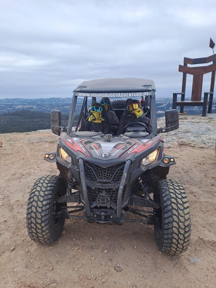 A Can-Am off-road vehicle on a dirt path with a scenic view in the background. 1