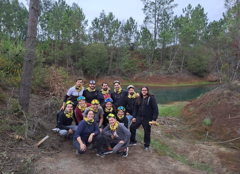 A group of people in outdoor gear by a forested area with a body of water. 2