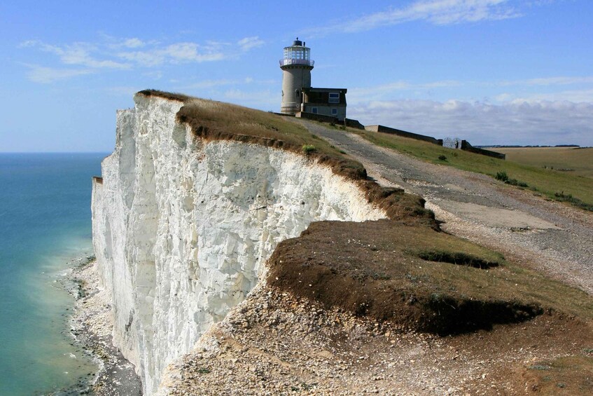 A coastal cliff with a lighthouse, a gravel path, and a grassy area. 4
