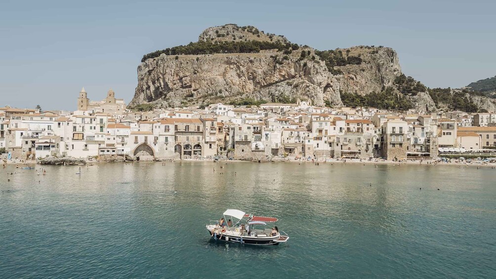 A coastal town with a prominent rock formation and a boat in the water. 5
