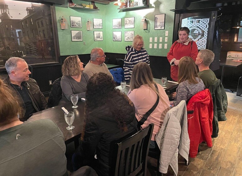 A group of people seated at a table in a restaurant with green walls and framed pictures on the wall. 2
